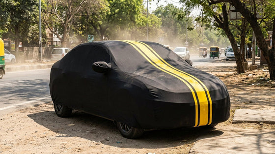 A car under a snug black DriveCult cover parked in harsh Indian sun beside a dusty street